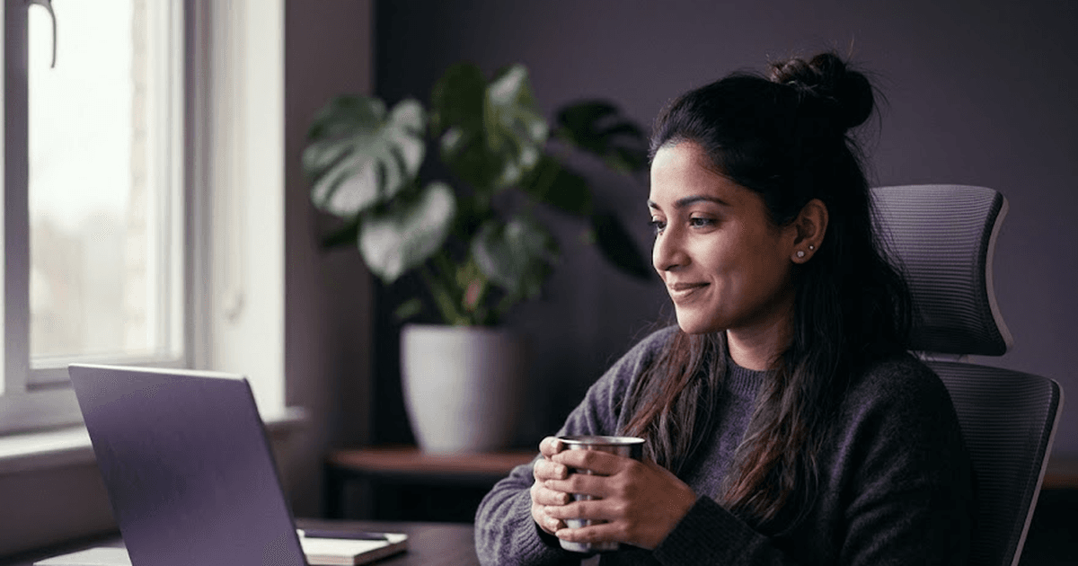 Indian woman analyst sipping chai at her home office desk on a Monday morning, laptop with purple glow